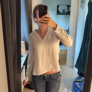 Vit blus med v-ringning och slits - Säljer en stilren vit blus med v-ringad hals och långa ärmar med knäppning vid mudden. Blusen har en rak passform och slits i sidorna, vilket ger en snygg och avslappnad look. Perfekt till jeans eller kjol för en fräsch outfit. Perfekt blus för konferenser eller liknande🫶🏻