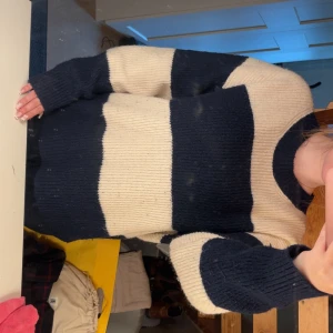 Randig stickad tröja i blått och beige - Säljer en oversized stickad tröja med breda marinblå och beige ränder. Tröjan har rund halsringning och långa ärmar, perfekt för dig som gillar en chill och avslappnad stil. Supermjuk och skön att ha på sig under kyliga dagar.