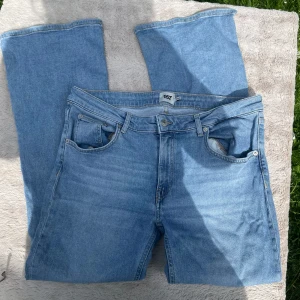 Ljusblå bootcut jeans 157 XL - Snygga ljusblå bootcut jeans från 157 i storlek XL Short. Klassisk femficksmodell med låg midja och raka, utsvängda ben. Perfekta för dig som gillar retrovibbar och vill ha ett par jeans med skön passform och cool look.