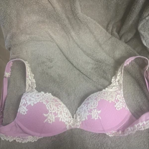 Rosa Intimissimi bh - Supersöt ljusrosa bh med vita spetsdetaljer och blommigt mönster. Kuporna är vadderade och har en snygg form, perfekt för att ge lite extra lyft. Axelbanden är justerbara och spetsen ger en romantisk vibe.  Pris går att diskutera. 💗