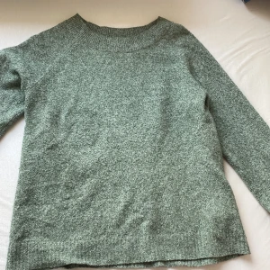 Grön stickad tröja från Vero Moda - Mysig grönmelerad stickad tröja från Vero Moda i storlek S. Tröjan har rund halsringning, långa ärmar och en relaxed passform. Perfekt för lager-på-lager och chill dagar. Enkel och stilren design som funkar till det mesta.