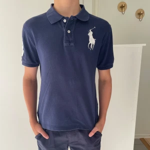  Polo Ralph Lauren Piké - Säljer en marinblå polo Ralph lauren Piké! Killen på bilden är c.a 170cm och piken sitter litet. Tröjan har inga spår efter defekter eller liknande. Tveka inte det minsta på att höra av er vid minsta fundering gällande storlek eller annat!! Bundle är möjligt!