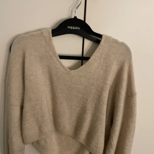 Beige stickad tröja från H&M - Mysig beige stickad tröja från H&M med v-ringad hals och avslappnad passform. Perfekt för lager-på-lager och passar till både jeans och kjol. Långärmad och i mjukt material som känns skönt mot huden.