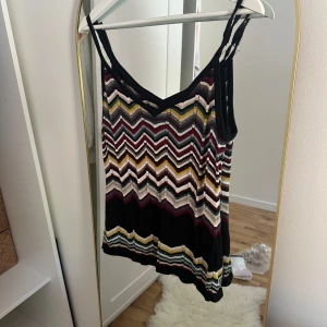 Missoni zigzag mönstrad linnetopp - Säljer en ikonisk linnetopp från Missoni med färgglatt zigzag-mönster i svart, vinröd, gul, beige, blå och silver. Tunt stickat material med smala axelband och v-ringning. Perfekt för dig som vill sticka ut med en färgstark och trendig look.