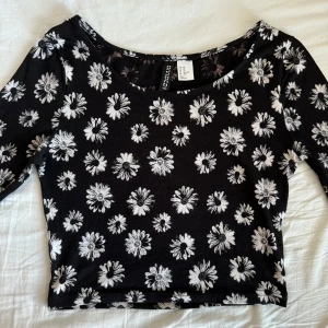 svart blommig topp - Snygg svart topp med vita blommor från H&M Divided. Den har långa ärmar och en croppad passform. Materialet är mjukt och stretchigt. Har bara använts ett fåtal gånger. Pris kan diskuteras! 🌸