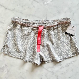 Calvin Klein Sleepwear shorts XS - Pyjamasshorts i silkesmjuk viskos i kort modell. De har resår och dragsko i midjan samt kort slits i sidorna. Shortsen är helt nya och aldrig använda, har fortfarande original tags sitter kvar i plagget. Storlek XS