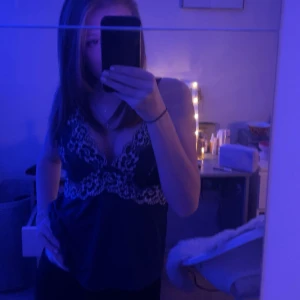 Mörkblå linne med matchande shorts med spetsdetaljer - Snygga mörkblå shorts och matchande linne med vita spetsdetaljer längs bensluten. De har en loose passform och elastisk midja för extra komfort. Perfekta för sommarnätter eller som mysiga pyjamasshorts. Materialet känns mjukt mot huden och spetsen ger en extra touch av stil.