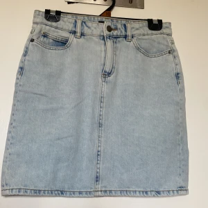 Ljusblå jeanskjol från Lindex storlek 34 - Snygg ljusblå jeanskjol från Lindex i klassisk femficksmodell. Kjolen har bälteshällor, knapp och dragkedja framtill samt raka sömmar. Perfekt för dig som gillar en enkel och stilren look. Passar till allt och är superenkel att styla.