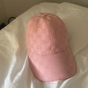 Rosa GG keps med monogram - Snygg rosa keps f med klassiskt GG-monogram i ton-i-ton. Kepsen har böjd skärm, justerbar rem baktill med gulddetalj och är tillverkad i bomullsmix. Perfekt accessoar för att lyfta din outfit med en lyxig touch.