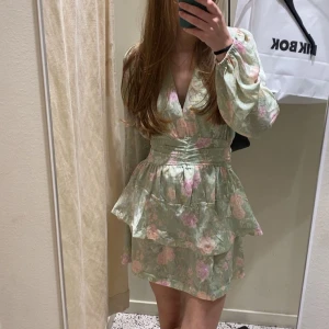 Grön blommig kortklänning med volang - Superfin ljusgrön kortklänning från Bikbok, säljer denna åt en kompis då hon ej var nöjd med den. Endast testad. Nypris 700kr! 