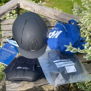 Svart ridhjälm från KEP Italia, strl L - Säljer en svart ridhjälm från KEP Italia i storlek 58. Hjälmen har en matt finish, snygg ventilation framtill och justerbart hakband i svart läder. Medföljer originalpåse och extra innerpad. Perfekt för dig som vill ha stilren och säker look i stallet. Nypris 3499