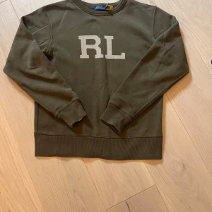 Olivgrön sweatshirt från Polo Ralph Lauren - Säljer en olivgrön sweatshirt från Polo Ralph Lauren i storlek XS. Tröjan har RL-tryck på bröstet, den är också nästan helt ny!Jag på bilden har fixat så att den ska se mindre ut men jag är 155 och skulle säga att den passar upp till 170.Pris kan alltid diskuteras och sänks alltid vid en snabb affär!