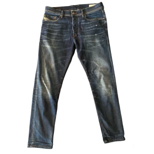 Diesel slim jeans - Snygga Diesel jeans i mörkblå tvätt med slitningar. Jeansen har detaljerade sömmar och logotyp på fickan. Perfekta för en avslappnad och trendig look. Storlek W32 L30, Slim fit.