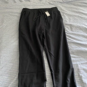 Svarta linnebyxor  - Svarta linnebyxor i avslappnad modell med resår och snörning i midjan. Byxorna har sidfickor fram och två bakfickor. Perfekta för chill dagar eller när du vill ha en clean och enkel stil.