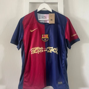 FC Barcelona Raphinha 11 Nike tröja M - FC Barcelona matchtröja från Nike i storlek M med Raphinha 11 på ryggen. Tröjan har klassisk halva röd och halva marinblå design, guldiga detaljer och klubbmärke på bröstet. Tillverkad i lätt och ventilerande material, perfekt för fotboll eller supporterliv.