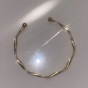 Guldigt armband & örhängen set - Säljer ett snyggt set med ett guldigt armband i vågig design med kulor i ändarna och ett par klassiska små guldiga hoops. Perfekt för dig som gillar stilrena och trendiga accessoarer som sticker ut lite extra. Aldrig använda! 🌸