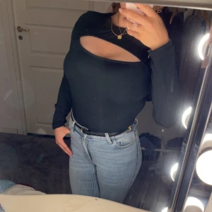 Svart långärmad topp med cut-out - Säljer en svart långärmad topp med en snygg cut-out detalj över bröstet. Toppen är tight och har en stilren design som passar perfekt till jeans eller kjol. Materialet känns mjukt och stretchigt.