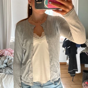 Ljusgrå kofta  - Säljer en ljusgrå tunn kofta från saint tropez med rund halsringning och knappar framtill. Perfekt att slänga över ett linne eller t-shirt. Enkel och stilren design som passar till det mesta.