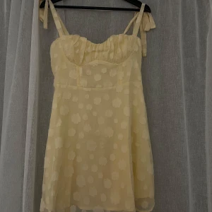Ljusgul blommig klänning från Hello Molly - Supersöt ljusgul kortklänning från Hello Molly med tunna axelband som knyts och subtilt blommönster. Tyvärr lite för kort för mig (jag är 173cm). Prislapp och förpackning finns kvar, alltså helt ny! Nypriset är 1100kr. 
