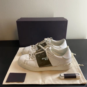 Valentino open  - Säljer ett par vita Valentino open skor i vit färg med sällsynt kontrastfärg i glansig olivgrönt. Storlek 43, passar + - 1 storlek. Box, dustbags, valentino kort och extra skosnören ingår i köpet. Köpta förra sommaren men inte mycket använda. Inga större skador på skorna. Finns några få slitningar men inte något som man märker. Annars är dem som nya. Äkta såklart ⭐️. Skriv om du undrar något. Betalar för frakten. Priset är inte ristat i sten👍