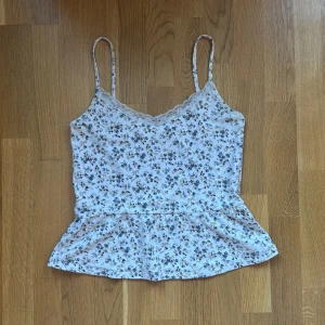 Blommig linnetopp med spets från Bik Bok - Söt vit linnetopp från Bik Bok med små blå blommor och spetsdetalj vid urringningen. Smala axelband och volang nertill ger en feminin look. Perfekt för varma dagar. Toppen är i storlek L men jag skulle säga att den funkar alldeles utmärkt för S/M till M också!