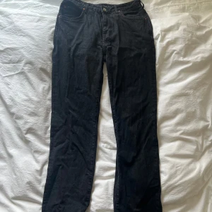 Svarta jeansbyxor från Never Denim - Säljer ett par svarta jeansbyxor från Never Denim i klassisk straight modell. Byxorna har fem fickor, bälteshällor och knappgylf. Perfekta för dig som gillar en enkel och stilren look.
