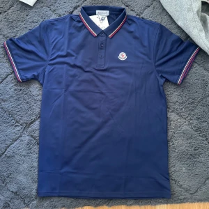 Mörkblå pikétröja från Moncler - Säljer en mörkblå pikétröja från Moncler med klassisk krage. Helt ny 999kr