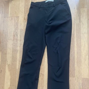 Svarta kostymbyxor från 157 - Svarta kostymbyxor från 157 med normal passform. Byxorna har hällor för bälte, snedställda fickor fram och stängs med dragkedja och knapp. Dom är i bra skick och använts bara ett par gånger. Passar även de med storlek S.