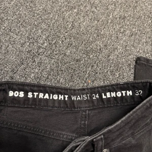 Svarta 90s straight jeans - Säljer ett par svarta jeans med rak passform och klassisk 90-talsstil. Byxorna har fem fickor, dragkedja och knapp framtill samt bälteshällor. Midjemått är 24 och längd 32. Perfekta för dig som gillar en tidlös look.