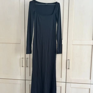 Svart långklänning från Gina Tricot - Säljer en svart långklänning från Gina Tricot med lång ärm och fyrkantig ringning. Klänningen har en tight passform och är tillverkad i ett mjukt, stretchigt material. Jättestretchig och skönt