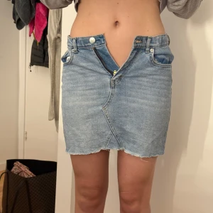 Blå jeanskjol från Levi's - Säljer en klassisk blå jeanskjol från Levi's, dragkedja och knapp framtill. Kjolen har en kort passform. 