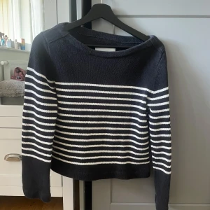 Svart och vit randig stickad tröja - Säljer en stickad tröja i svart med vita horisontella ränder. Tröjan har lång ärm och en klassisk, lite lös passform. Perfekt för dig som gillar en tidlös och stilren look.