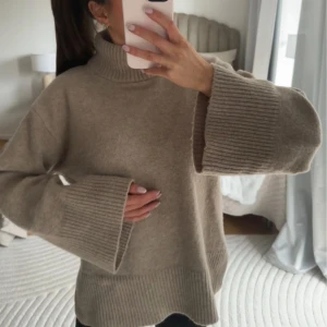 Beige stickad polotröja med vida ärmar - Säljer en beige stickad polotröja med breda, ribbade muddar och vida ärmar. Tröjan har en hög polokrage och är perfekt för lager-på-lager. Passformen är loose och materialet känns mjukt och varmt.