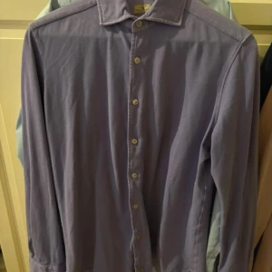 Ljuslila skjorta från Sonrisa - Säljer en stilren ljuslila skjorta från Sonrisa. Skjortan har klassisk krage, knäppning framtill med vita knappar och långa ärmar med manschett. Perfekt för dig som gillar en clean och snygg look. Nypris 2500
