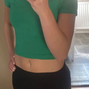 Grön croppad t-shirt - Säljer en enkel och snygg grön croppad t-shirt med korta ärmar. Perfekt till jeans eller shorts för en avslappnad stil.