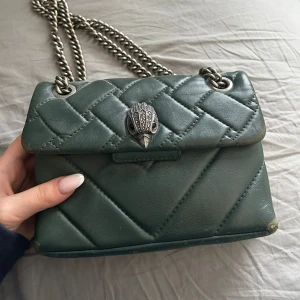Kurt Geiger väska  - Super fin grön axelväska från Kurt Geiger med quiltad design och silverfärgad kedja. Väskan har ett dekorativt spänne framtill och magnetlås. Den har sina defekter vilket man kan se på bilderna därför är priset ganska lågt. Nypris ligger på 2000❤️
