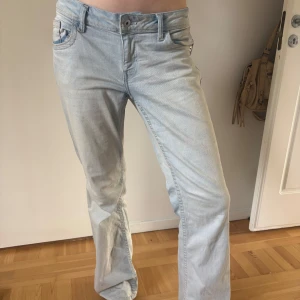 Ljusblå raka jeans - Säljer ett par ljusblå jeans med klassisk femficksdesign och raka ben. Jeansen har normal passform och stängs med dragkedja och knapp. Perfekta för en avslappnad stil och passar till det mesta.