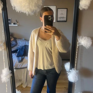 Beige stickad kofta från Lindex  - Mysig beige stickad kofta med lång ärm och avslappnad passform. Perfekt att slänga på sig över en topp för en enkel och stilren look. Koftan  har en öppen front utan knappar eller dragkedja.