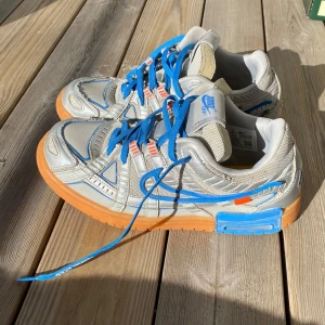 Nike Air Rubber Dunk Off-White UNC - Tja! Säljer mina Nike Air Rubber Dunk Off-White UNC i storlek 44.  De saknar den orangea tagen och den blå färgen under sulorna har börjat flagna lite grann, annars är de i bra skick! Saknar låda. Skickar på post (köparen betalar fraktkostnad) eller möts upp i Stockholm - söderort eller centralt. Ha det!