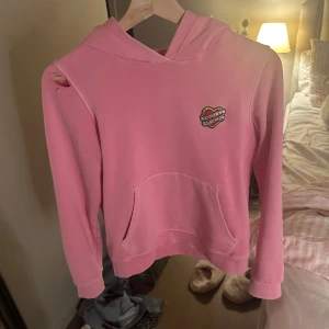 Zadig Voltaire tröja  - Säljer en rosa hoodie med huva och magficka. På bröstet finns ett broderat hjärta med textdetalj. Tröjan har långa ärmar och är i mjukt material, perfekt för en avslappnad stil. Hål vid ena axeln som lätt går att fixa där av priset