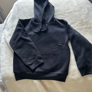 Svart hoodie  - Jättefin barn hoodie!😊 Den är markerad som storlek 146-152 men den är mycket liten i storleken. Skulle säga att den passar 122-128. Helt ny, säljer eftersom storleken inte passade. Säljer en likadan fast i grå också! Så kolla in på min profil om du är intresserad!😊😊 Säg till om du har några frågor!