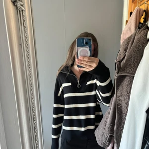 Svart och vit randig stickad tröja - Säljer en svart stickad tröja med vita horisontella ränder och halv dragkedja vid halsen från VERO MODA.