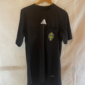 Domartröja - Svart kortärmad domartröja som jag köpte 2024. Säljer eftersom jag inte dömer längre. Nypris ligger på 549kr. Har även än långärmad gul domartröja, även den från 2024 samt en visselpipa till salu också!