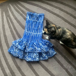 Blåvit volangklänning med mönster - Supersöt blåvit klänning med smock upptill och volanger nertill. Klänningen har ett unikt mönster och är ärmlös, perfekt för varma dagar. Materialet känns lätt och luftigt, och modellen är kort. Perfekt för dig som vill sticka ut! Köpt på Plick för 1000 ❤️