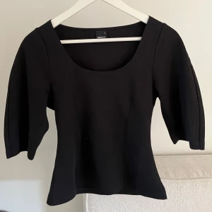 Topp - Snygg svart topp från Gina Tricot med rundad urringning och trekvartsvida ärmar. Toppen har en figurnära passform.
