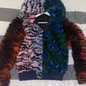H&M x KENZO Faux Fur Multicolour Hoodie – Strl M – Ikonisk Limited Edition - Sällsynt chans att lägga vantarna på en ikon från H&M x Kenzo-kollektionen 2016! Detta är den färgsprakande faux fur-hoodien/jackan som blev ett av de mest hypade plaggen från samarbetet – slutsåld direkt vid release. Pris går att diskutera.  Detaljer: 	•	Storlek: M (passar unisex) 	•	Material: Fuskpäls (polyester), helfodrad 	•	Skick: Väldigt fint vintage-bruksskick – inga fläckar, hål eller defekter 	•	Originalpris: ca 2000 kr 	•	Samlarvärde – populär bland fashionistas