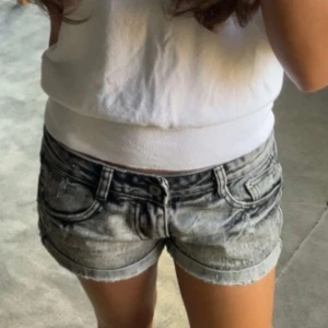 Grå jeansshorts  - Snygga grå jeansshorts med slitna detaljer och uppvikta benslut. Klassisk femficksmodell med knapp- och dragkedjestängning. Märke på baksidan och logga på ena bakfickan. Perfekta för varma dagar. Köpta på Vinted men säljer då det ej passade. 