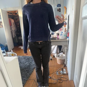 Mörkblå tröja med stjärndetalj - Säljer en mörkblå sweatshirt med långa ärmar och dragkedjor i sidorna. Tröjan har en vit stjärna broderad på ena ärmen och är i mjukt material. Perfekt för en avslappnad stil.