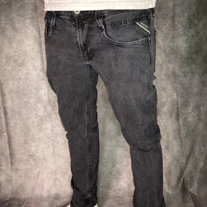 Replay jeans  - Säljer ett par svarta Replay jeans med klassisk femficksdesign och diskret logga på fickan. Jeansen har normal passform och raka ben, perfekt för en stilren look. Snygga detaljer vid fickorna och knappgylf.