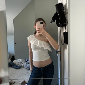 Off shoulder top - Säljer en vit, ribbad oneshoulder topp med volangdetalj längs axeln perfekt till sommaren.🩷